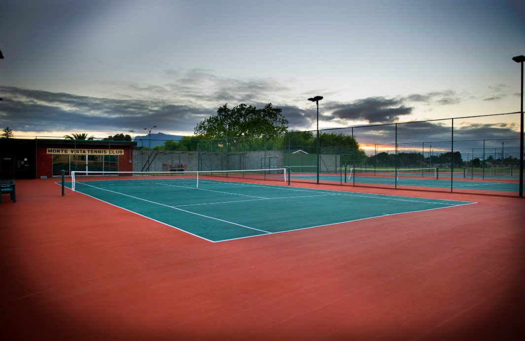 Monte Vista Tennis Club courts at dusk, with the clubhouse and court signage visible